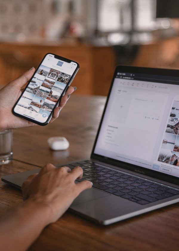 Woman edits social media content on phone and laptop at a cafe in Bali.
