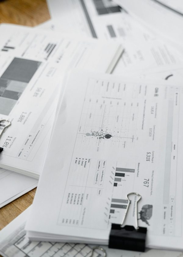 A stack of financial reports and graphs with clips on a wooden desk, highlighting business planning.